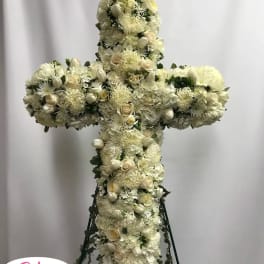 White floral cross arrangement on a stand