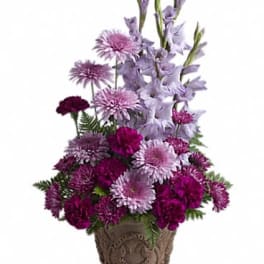Tall arrangement of lavender and deep purple flowers in a decorative brown pot