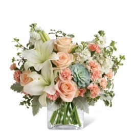 Bouquet of peach roses and white lilies in a clear glass vase