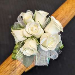 Small cluster of white roses with silver ribbon arranged as a wrist corsage