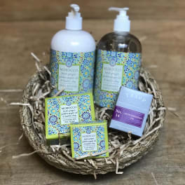 Spa gift basket with soap, lotion, and a candle in a woven tray