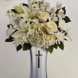 White floral arrangement in a silver vase with a cross