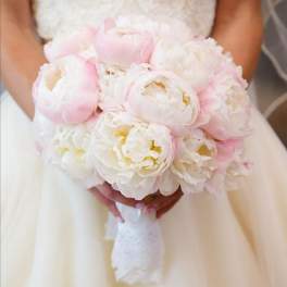 Round bridal bouquet of white and pale pink peonies wrapped with white lace