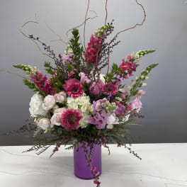 Pink and white floral arrangement in a purple vase