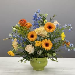 Mixed bouquet in a green vase with orange and blue flowers
