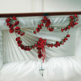 Red rose garland draped over white satin with a hanging crucifix