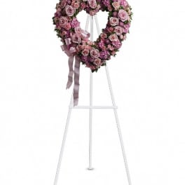 Heart-shaped pink floral wreath on a white easel