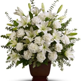 White lilies and roses arranged in a brown urn vase