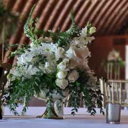 White floral centerpiece in a gold pedestal vase