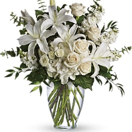 White lilies and roses arranged in a clear glass vase