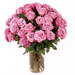 Large bouquet of pink and lavender roses arranged in a clear glass cylinder vase