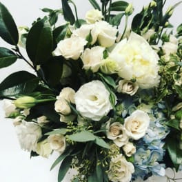 White roses and pale blooms arranged with dark green foliage