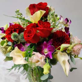 Bouquet of red roses, white calla lilies, and purple orchids in a vase