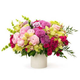 Low arrangement of pink roses, purple mums, and green orchids in a white cylinder vase