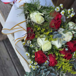 Bouquet of red and white roses with small daisies in white wrap