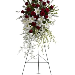 Standing spray of red roses and white lilies with orchids on a tall metal easel