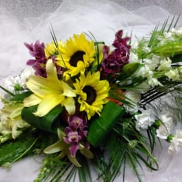 Bouquet with sunflowers, lilies, and purple orchids on white fabric