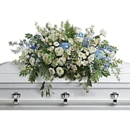 White and blue casket spray of mixed flowers on a light-colored casket
