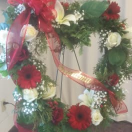Heart-shaped floral wreath with red and white flowers on a stand