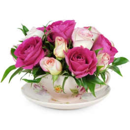 Pink and white roses arranged in a floral teacup with saucer