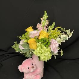 Pink teddy bear with a pastel flower arrangement in a pink vase