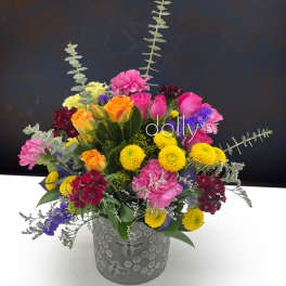Mixed bouquet in a gray vase with pink, yellow, orange, and purple flowers