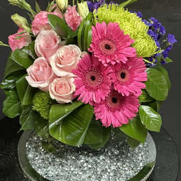 Pink roses and gerbera daisies in a low glass vase