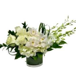 Low white rose and orchid arrangement with hydrangea in a clear glass cylinder vase