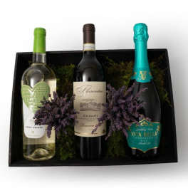 Gift box with three assorted wine bottles nestled in moss with purple dried sprigs