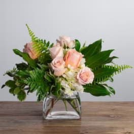Pink roses and white flowers in a clear glass vase