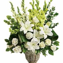 White lilies and green flowers arranged in a decorative vase