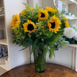 Bouquet of yellow sunflowers in a tall glass vase