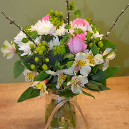 Mixed bouquet of pink roses, white daisies, and alstroemeria in a glass jar