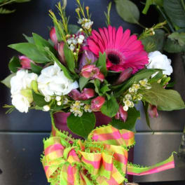 Bouquet of pink gerbera daisies and white flowers with a bright striped ribbon