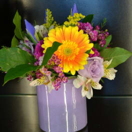 Colorful bouquet in a lavender vase with a large yellow-orange gerbera daisy