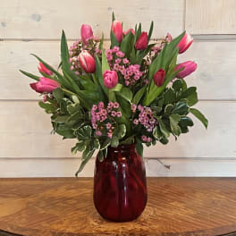 Pink tulips and small pink flowers in a red glass vase