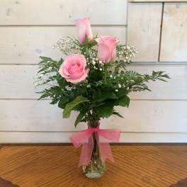 Pink roses in a clear glass vase with a pink ribbon