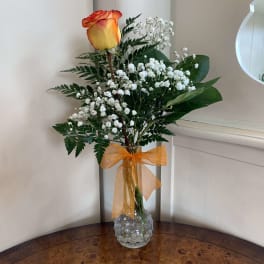 Orange rose in a clear glass vase with white baby's breath