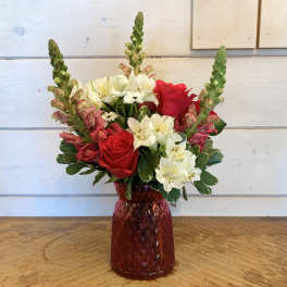 Red roses and white alstroemeria in a red glass vase