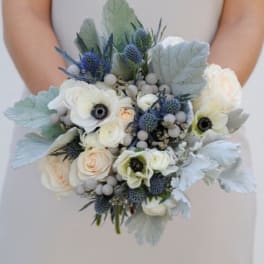 Wedding bouquet of white and pale peach flowers with blue thistle accents