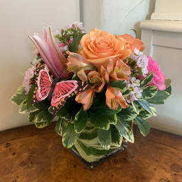 Mixed bouquet in a square glass vase with a butterfly decoration