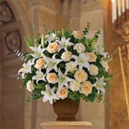 White lilies and peach roses arranged in a brown urn vase