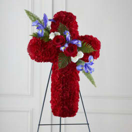 Red floral cross on a stand with blue and white accent flowers