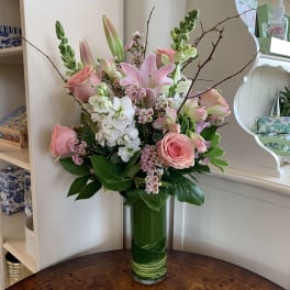 Pink lilies and roses arranged in a tall green vase