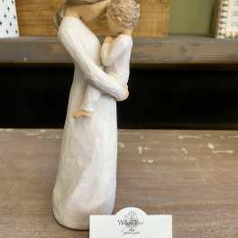 Wooden figurine of a woman holding a child, with a small display card