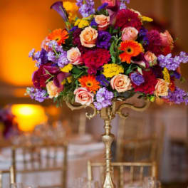 Tall floral centerpiece with roses, calla lilies, and gerbera daisies in a gold stand