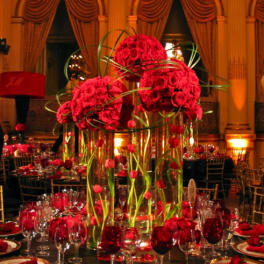 Tall red rose centerpieces in glass vases on a formal banquet table
