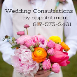 Person holding a colorful bridal bouquet with pink, orange, and yellow flowers