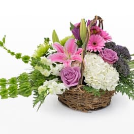 Basket arrangement with pink lilies, roses, and white hydrangeas