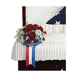 Red, white, and blue floral spray on a white-draped casket